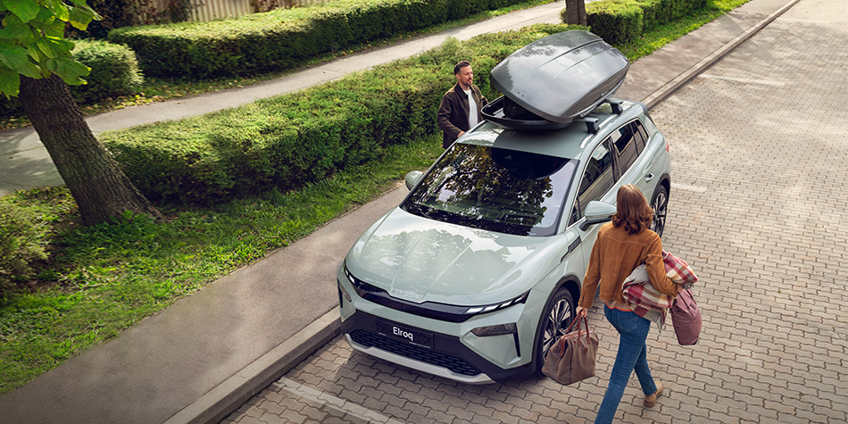 High angle of an Elroq with people walking towards the door, with rooftop storage on the car