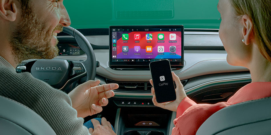 Two people in the front seats of a car connecting a phone