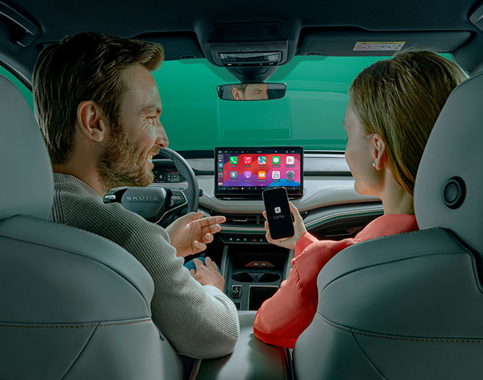 Two people in the front seats of a car connecting a phone