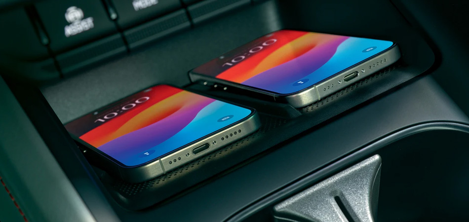 Two mobile phones charging in a wireless charge box in a cars centre console