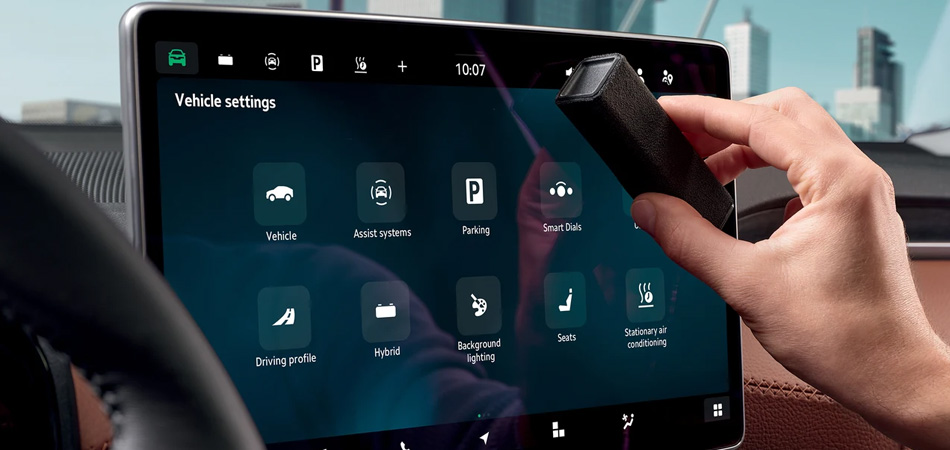 A hand using a screen cleaner on a Skoda infotainment screen in a Kodiaq SUV